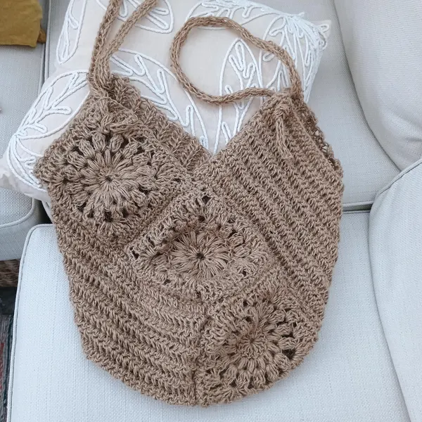 Beige flower granny square crochet bag arranged on a light chair.
