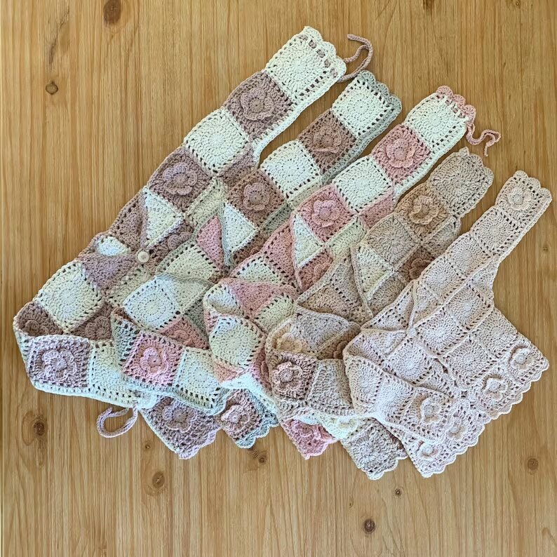 Several pastel crochet cardigan color combinations arranged on a wooden table.