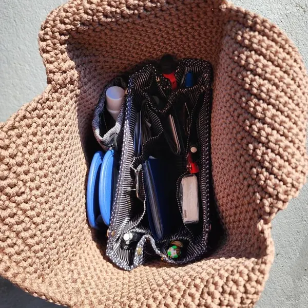 Interior view of a crochet tote bag fitted with a multi-pocket organizer.
