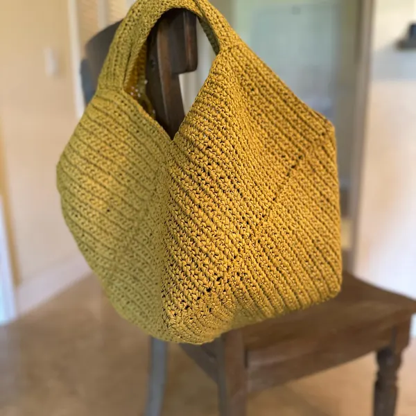 Mustard yellow crochet hobo bag with a wide integrated handle.