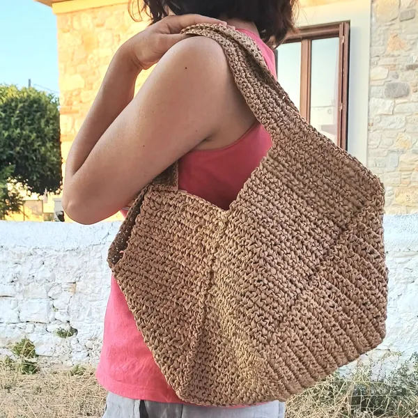 Large natural raffia crochet summer tote carried over the shoulder.